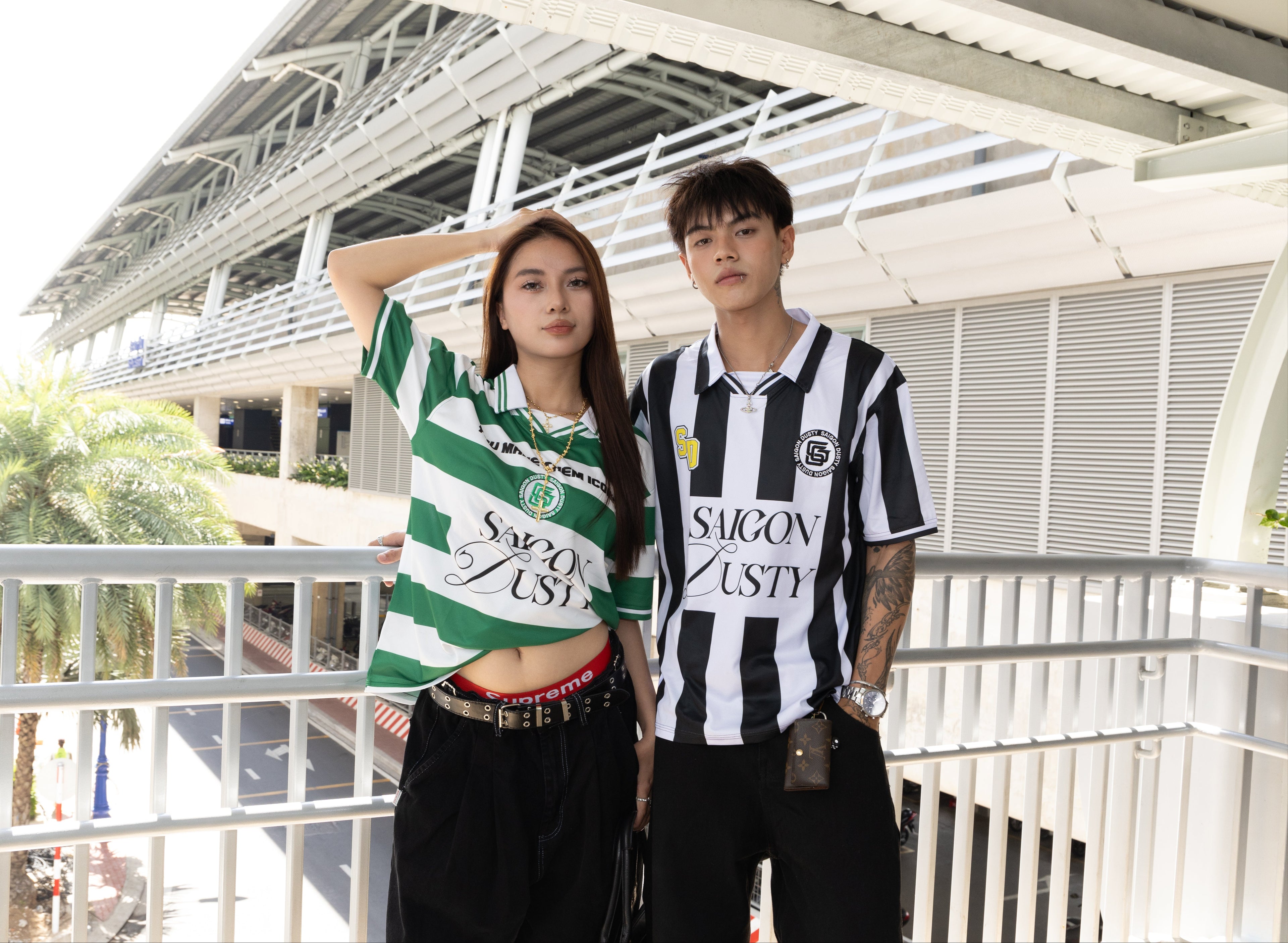 Two people wearing sports jerseys standing outdoors with a building in the background.